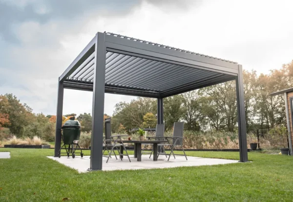 Nowoczesna pergola z dachem z listew stoi na patio, osłaniając stół i cztery krzesła - to eleganckie zadaszenie tarasu otoczone jest zielonym trawnikiem i drzewami pod częściowo zachmurzonym niebem.